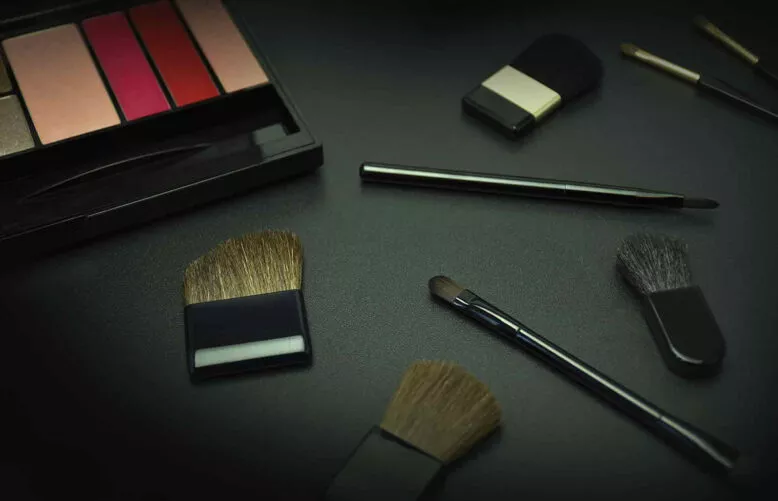 Applicateurs et pinceaux cosmétiques avec palette de maquillage sur fond noir