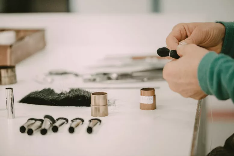 Fabrication artisanale de pinceaux cosmétiques avec fibres vegan sur une table d’atelier