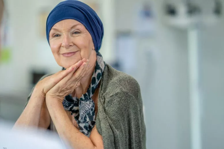 Femme souriante portant un foulard, image illustrant un programme de mécénat beauté pour les personnes atteintes de cancer