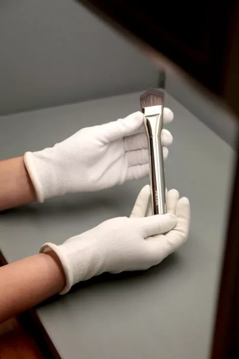 Gloved hands inspecting a high-end brush for quality control