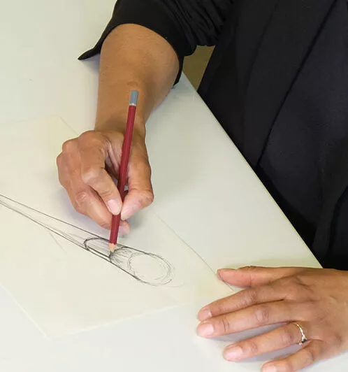 Designer drawing a custom makeup brush concept with pencil and brushes sample on desk