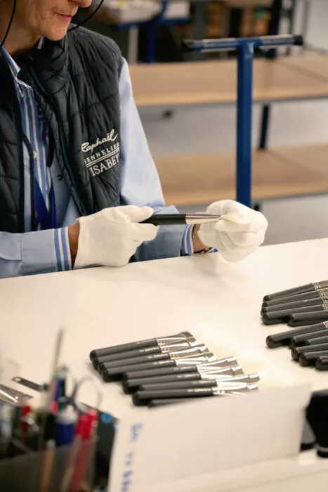 Inspection d’un pinceau cosmétique par une opératrice en gants blancs dans un atelier moderne