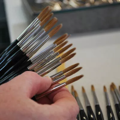 Vérification de pinceaux fins à la main, illustrant la rigueur du contrôle qualité artisanal