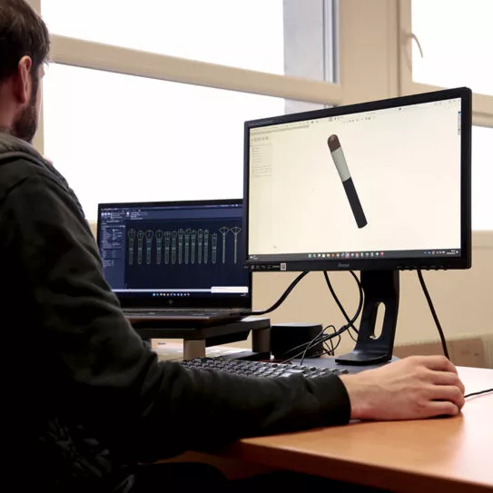 Ingénieur en conception 3D modélisant un pinceau cosmétique sur double écran dans un bureau technique