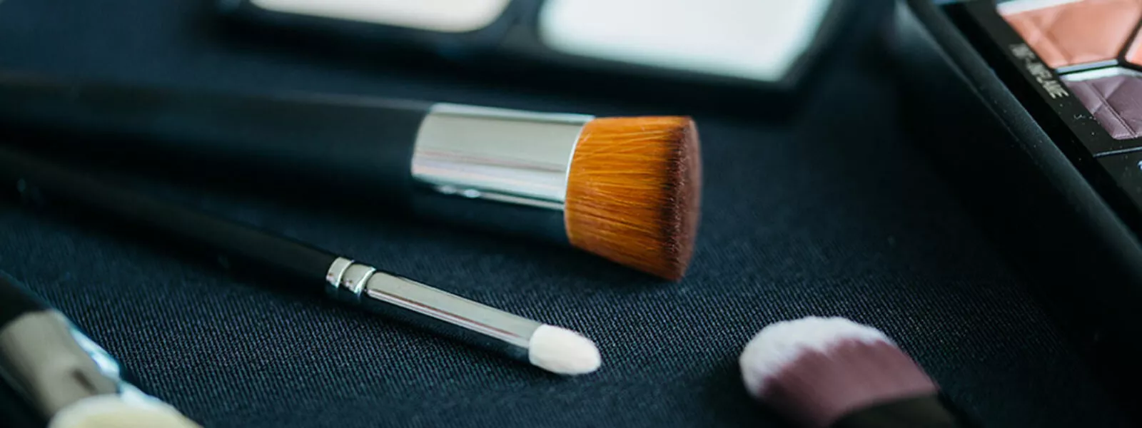 Flatlay of professional makeup applicators and brushes on black background