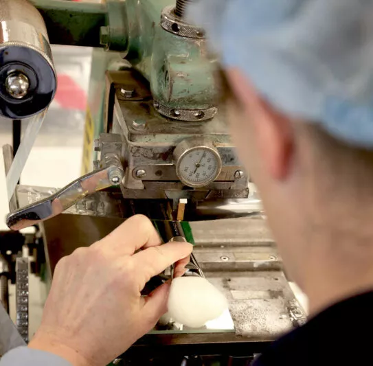 Pincelière procédant au marquage d’un pinceau avec une machine de précision dans les ateliers Raphaël