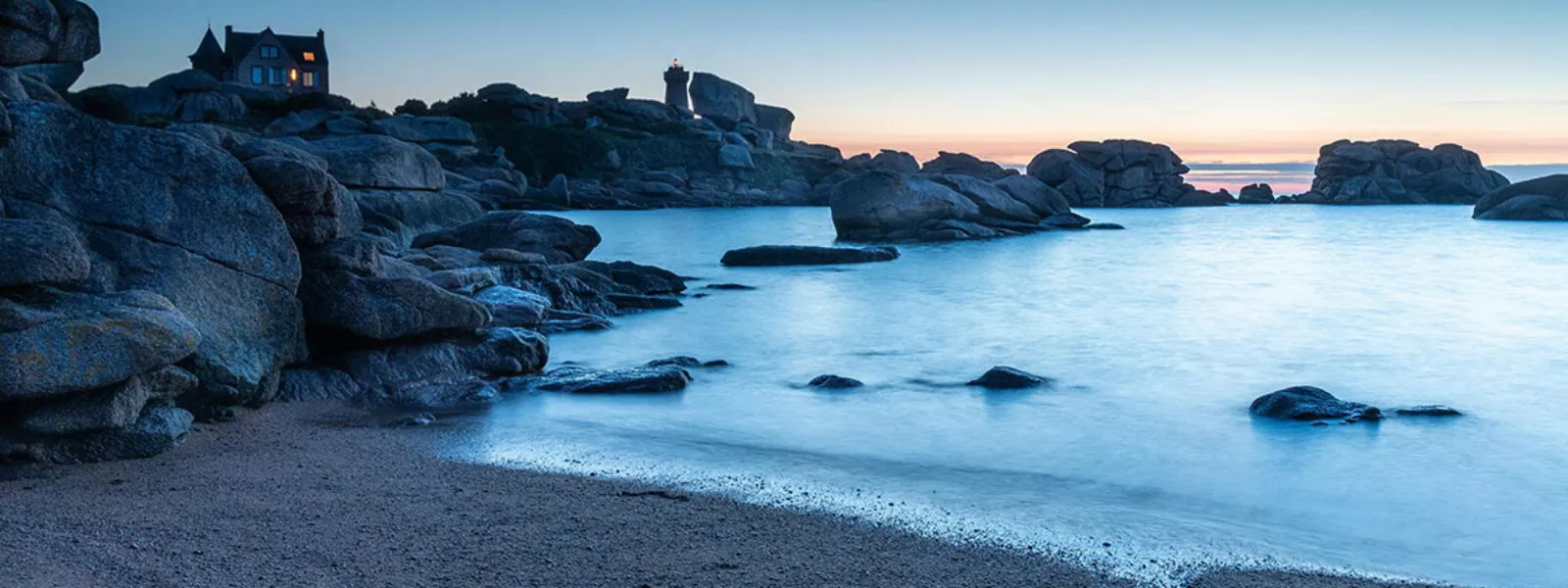 Paysage côtier de Bretagne au crépuscule, avec maison et phare sur les rochers
