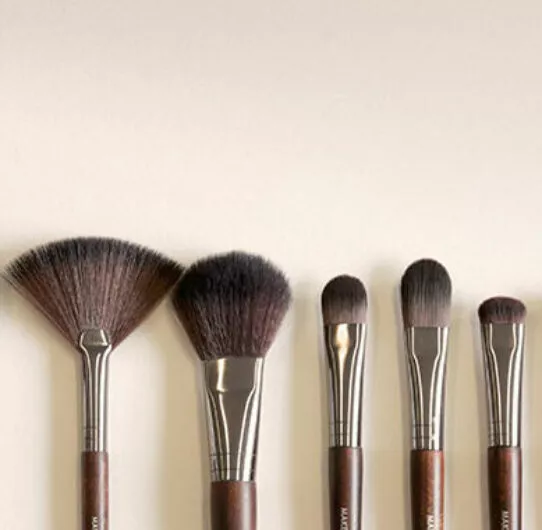 Collection de pinceaux de maquillage sur mesure alignés sur fond neutre