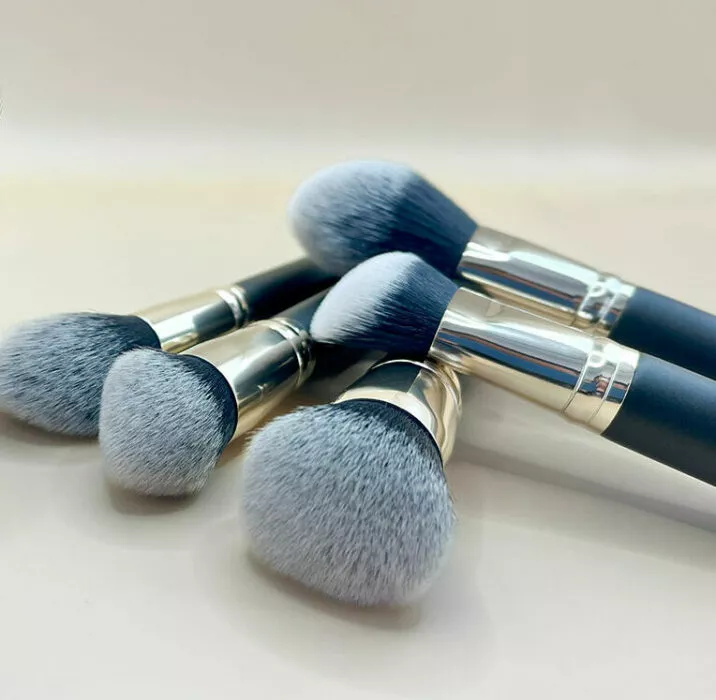Pinceaux teint Raphaël sur mesure à poils gris et noirs, posés sur fond beige clair