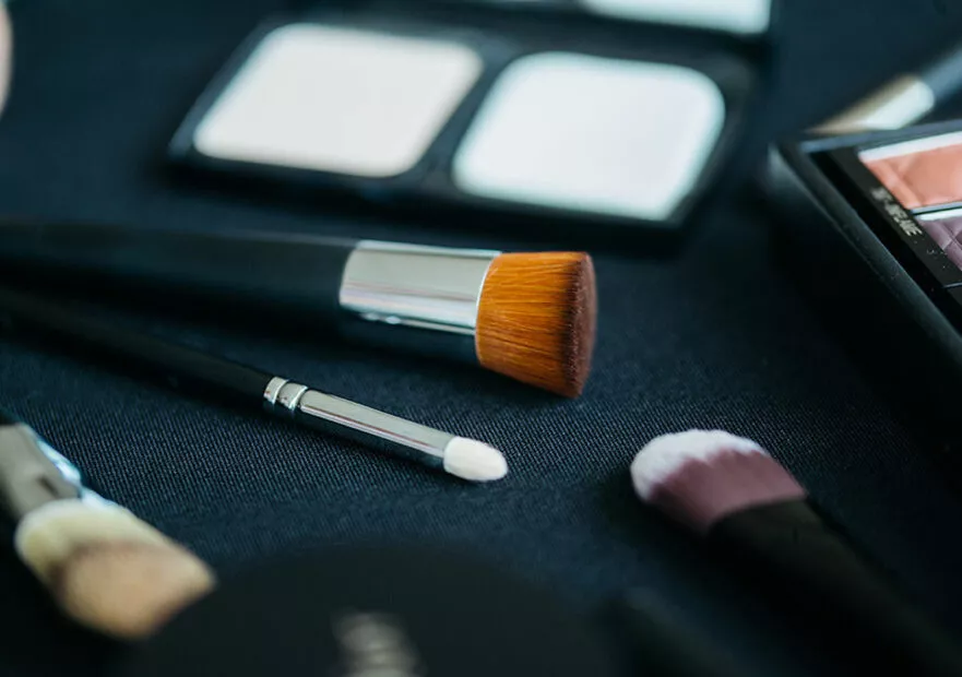 Pinceaux de maquillage professionnels sur plan de travail, accompagnés de palettes de maquillage