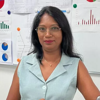 Portrait of Aruna, Quality Manager at Raphaël, sitting at her desk with performance charts in the background