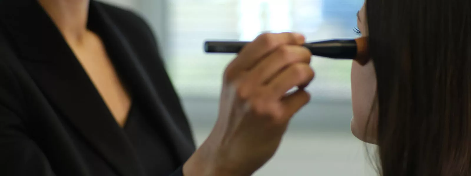 Professional makeup brush being tested on a model’s face during product development session – performance check at Raphaël