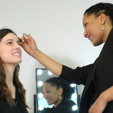 Makeup artist smiling while applying eyebrow makeup using a Raphaël brush