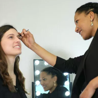 Makeup artist smiling while applying eyebrow makeup using a Raphaël brush