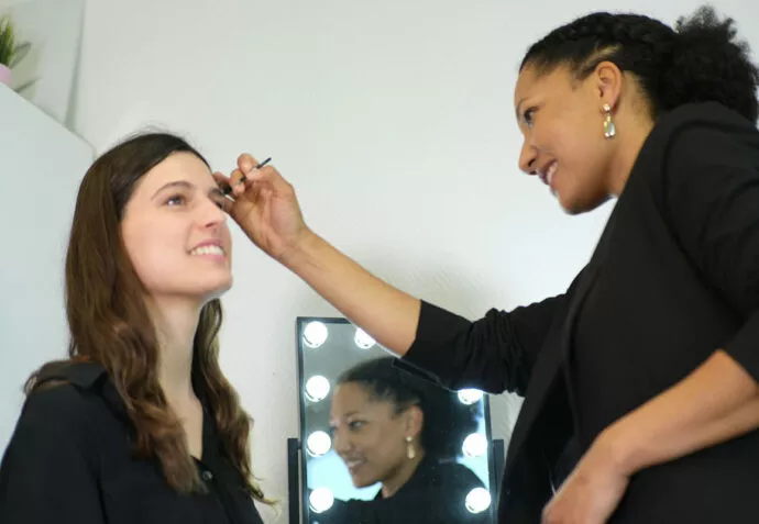 Makeup artist smiling while applying eyebrow makeup using a Raphaël brush