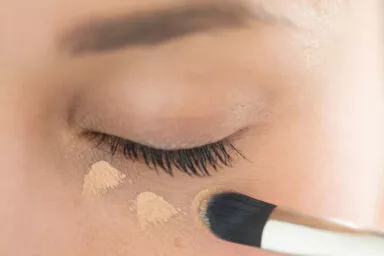 Application de correcteur avec pinceau cosmétique Raphaël sous les yeux