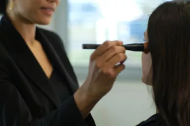 Maquilleuse professionnelle testant un pinceau Raphaël sur modèle en studio lumière naturelle