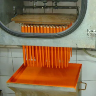 Machine automatisée plongeant des manches de pinceaux dans des bains de teinture orange et incolore